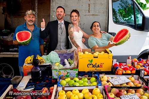 Una foto di sposi col fruttivendolo e banco di frutta colorata