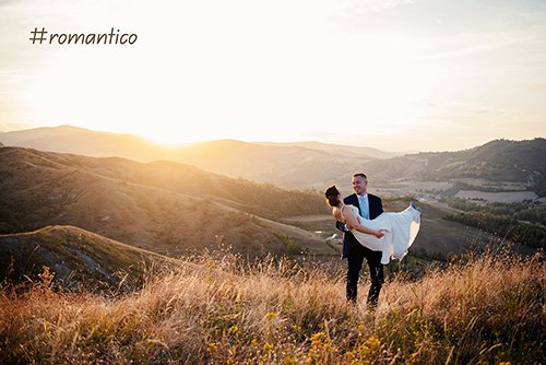 foto al tramonto lo sposo prende in braccio la sposa